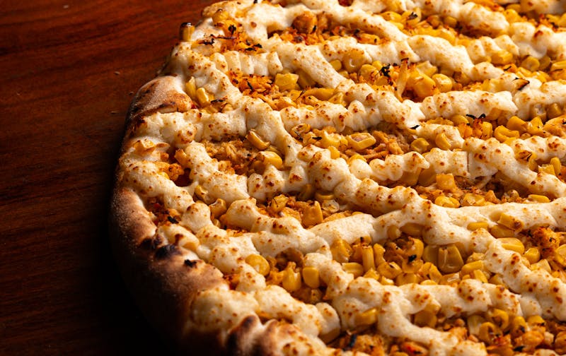 Punch pizza being prepared in wood-fired oven